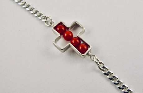 Une chaîne maille gourmette et 4 perles 4 mm de véritable corail rouge de Méditerranée, délicatement enchâssées dans une croix ajourée,  en argent 925/1000e