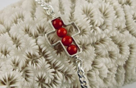 Une chaîne maille gourmette et 4 perles 4 mm de véritable corail rouge de Méditerranée, délicatement enchâssées dans une croix ajourée,  en argent 925/1000e