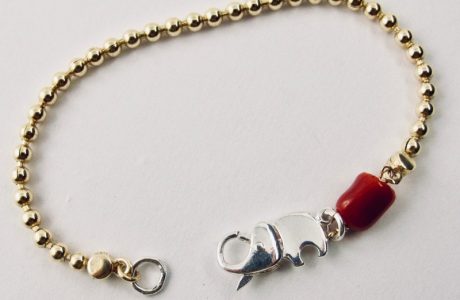 Le bracelet Kokkiri, avec son fermoir en forme d'éléphant en argent 925/1000e, est composé d'une chaîne boule en argent plaqué or et d'une grosse perle irrégulière de véritable corail rouge de Méditerranée