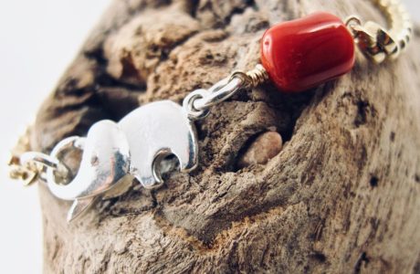 Le bracelet Kokkiri, avec son fermoir en forme d'éléphant en argent 925/1000e, est composé d'une chaîne boule en argent plaqué or et d'une grosse perle irrégulière de véritable corail rouge de Méditerranée