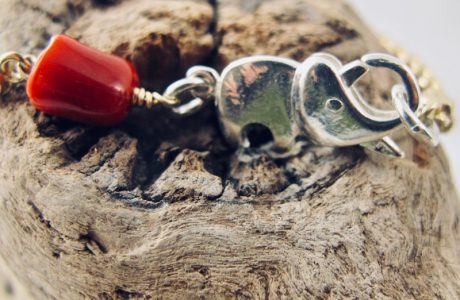 Le bracelet Kokkiri, avec son fermoir en forme d'éléphant en argent 925/1000e, est composé d'une chaîne boule en argent plaqué or et d'une grosse perle irrégulière de véritable corail rouge de Méditerranée