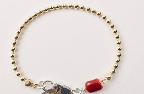 Le bracelet Kokkiri, avec son fermoir en forme d'éléphant en argent 925/1000e, est composé d'une chaîne boule en argent plaqué or et d'une grosse perle irrégulière de véritable corail rouge de Méditerranée