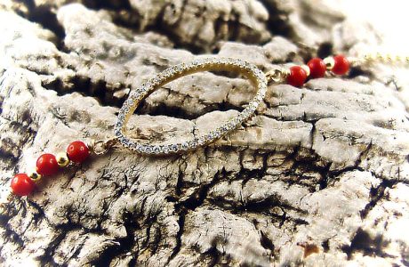 Ce bracelet est composé d'une fine chaîne en argent plaqué or et perles 2,5mm de véritable corail rouge de Méditerranée, reliée à un anneau ovale serti de cristaux de swarovski.