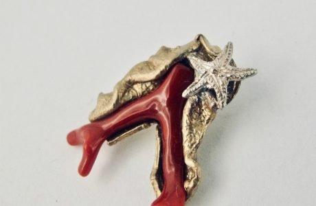Pendentif ramo,  branche de véritable corail rouge de Méditerranée enveloppée d'une feuille de bronze plaqué or, ornée d'une petite étoile de mer en argent massif.